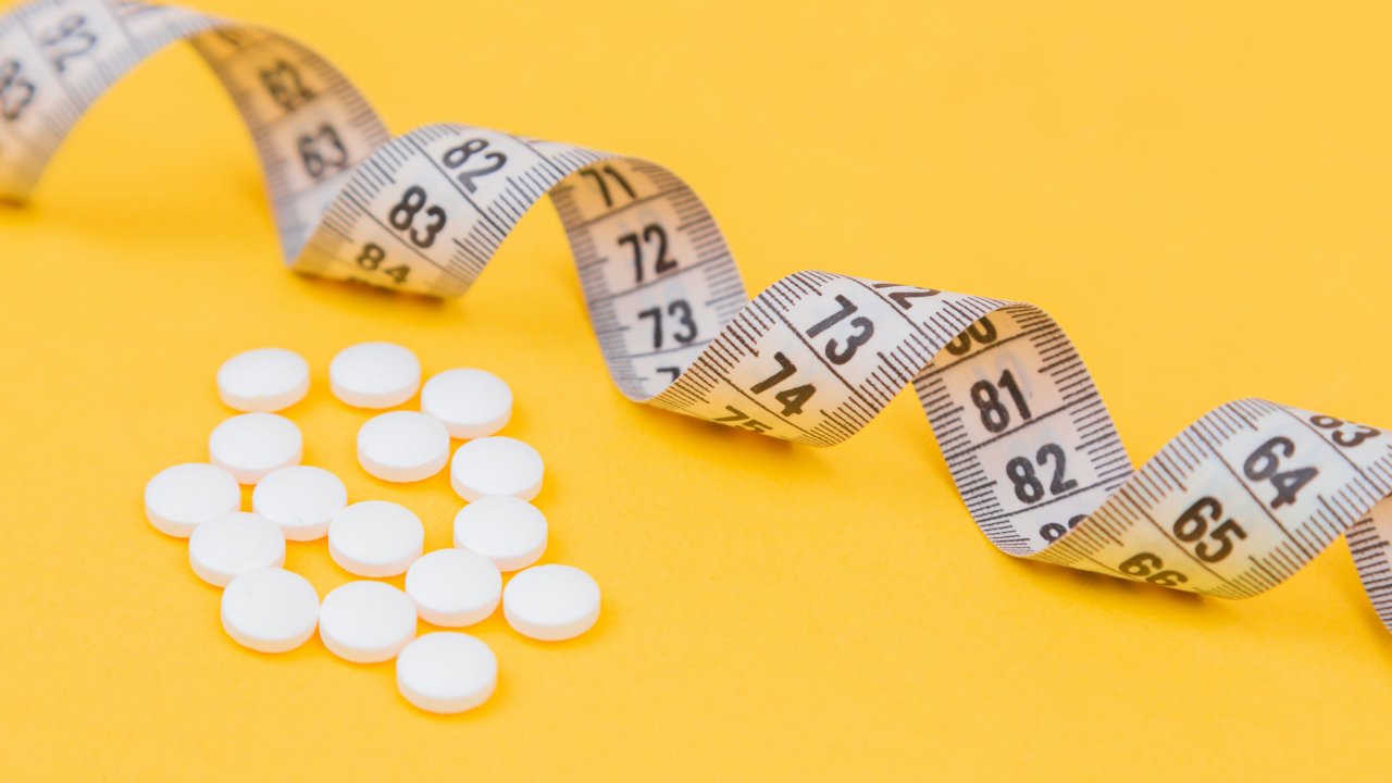 Foto de fita métrica para medir obesidade e com remédio para emagrecer ao lado