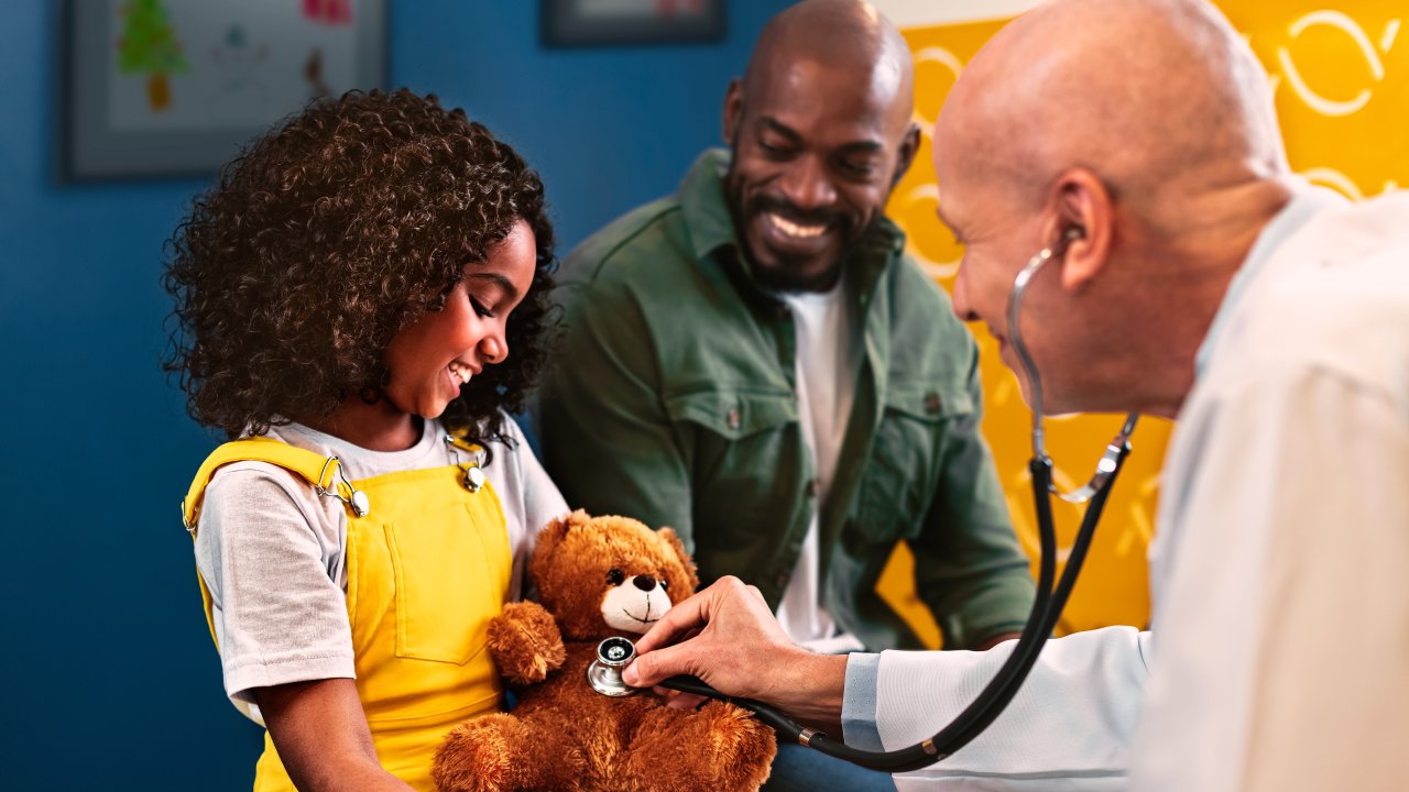 menina acompanhada do pai durante consulta médica