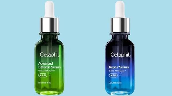 Dois frascos de s&eacute;rum Cetaphil com conta-gotas em fundo azul claro. &Agrave; esquerda, um frasco verde com Advanced Defense Serum AM. &Agrave; direita, um frasco azul escuro com Repair Serum PM. Ambos cont&ecirc;m 30 ml