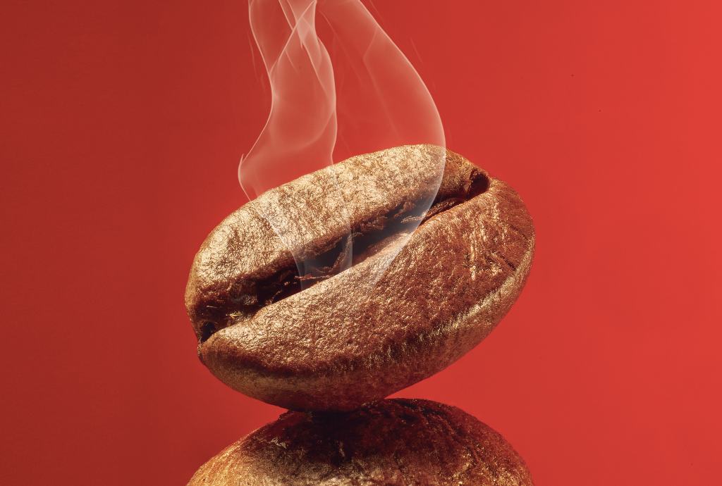 Grão de café torrado e brilhante, com vapor sutil subindo da fenda central, sobre um fundo vermelho vibrante